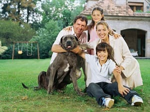 family with a dog sitting outside a home