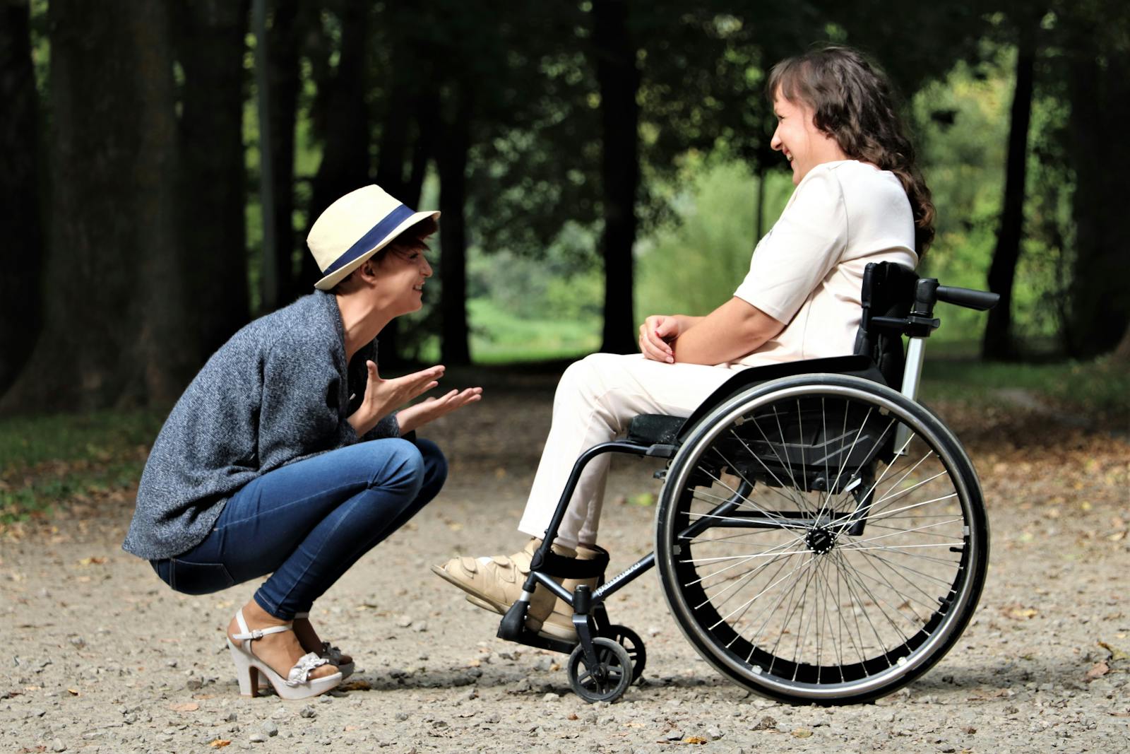 Disablity, Two women enjoy a lively conversation in a sunny park, embracing friendship and happiness.