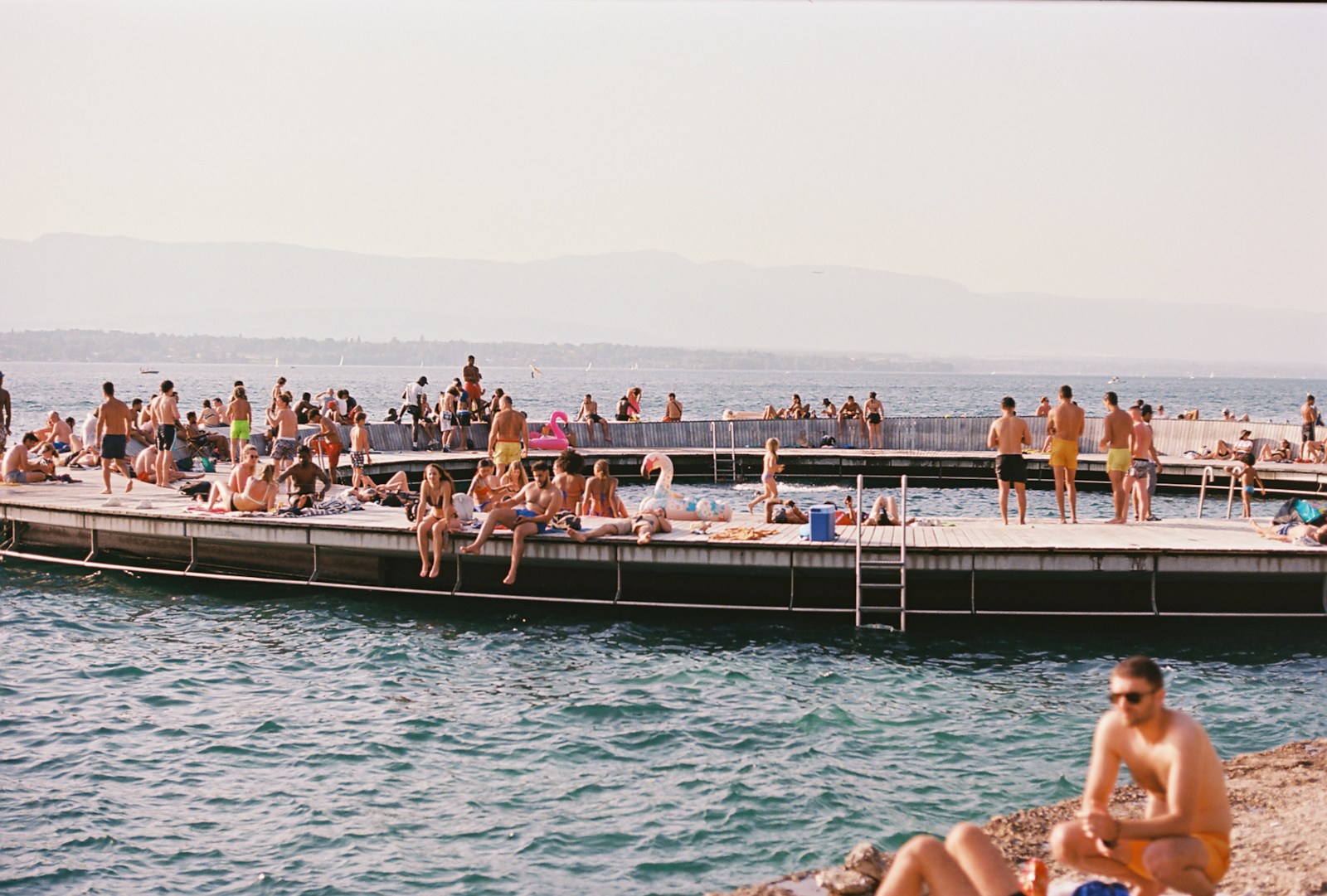 a group of people sitting on a pier next to a body of water